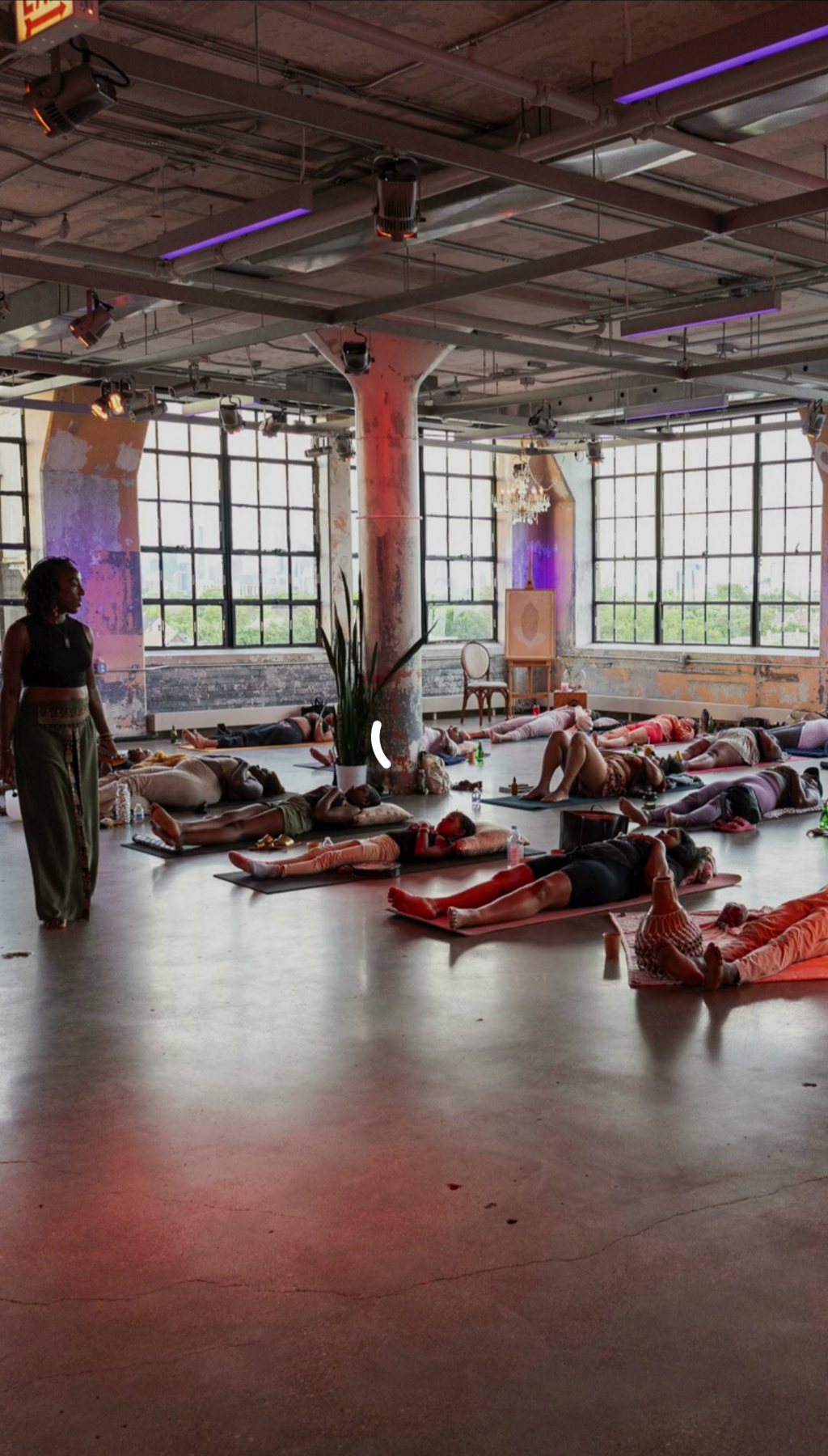 A wide view of a loft studio during a guided rest, mats laid out across the floor