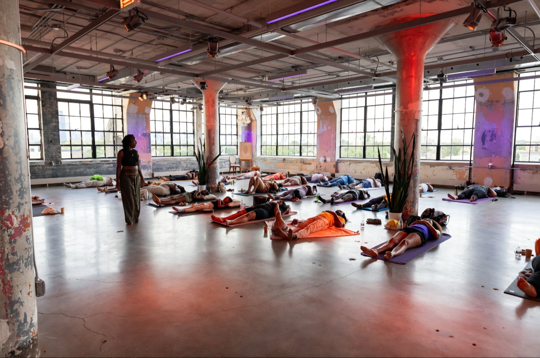 Participants resting at the end of a sound bath in a concrete loft studio lit by tall factory windows