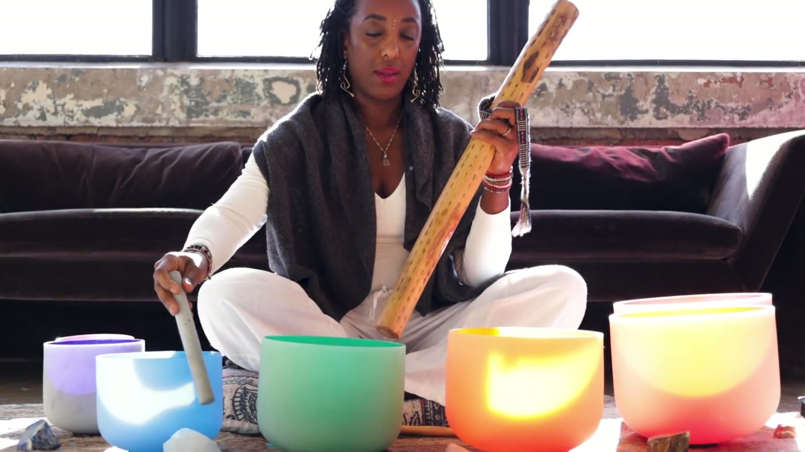Andrea seated on the loft floor with her crystal singing bowls, mid-session.